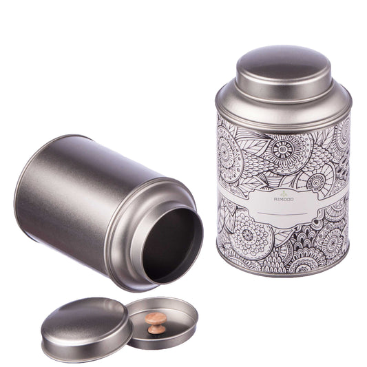 Zwei offene silberne Teedosen, eine mit Blumenmuster. Beide haben Aromadeckel und Etiketten.
