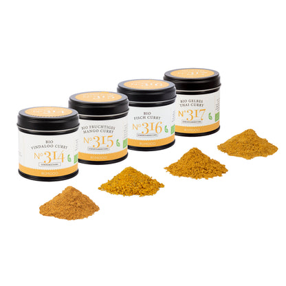 Vier Gläser Bio Curry Gewürz-Set N°2, davor passendes Häufchen gemahlenes Currypulver.