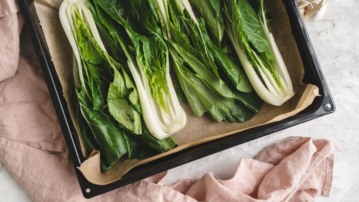 Frische Pak-Choi-Hälften ordentlich auf ein mit Backpapier belegtem Blech ausgelegt.