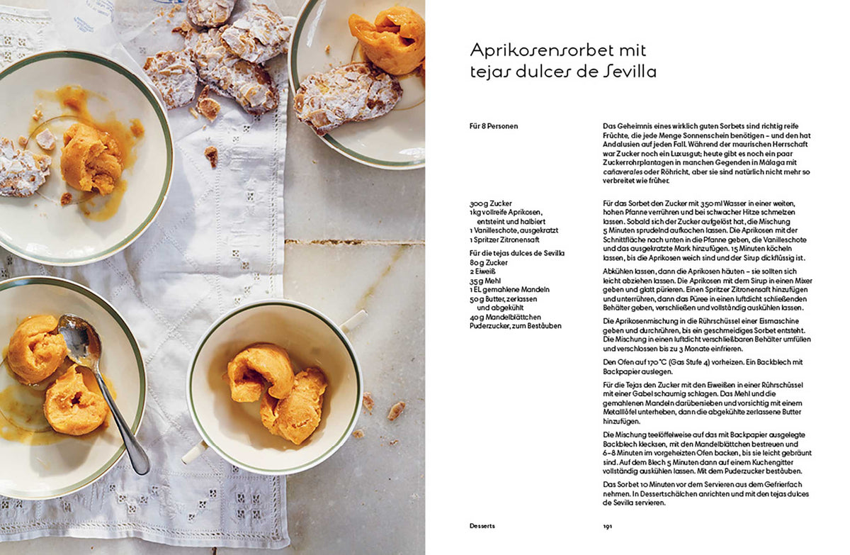 Drei Schalen Aprikosensorbet mit Löffeln auf Marmor, Gebäckstücke daneben.