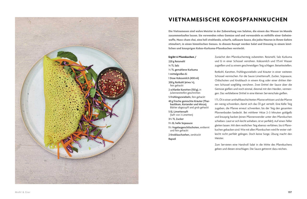 Gelber Banh Xeo-Pfannkuchen mit Gemüse und Dip auf einem Teller, daneben etwas grüner Salat.