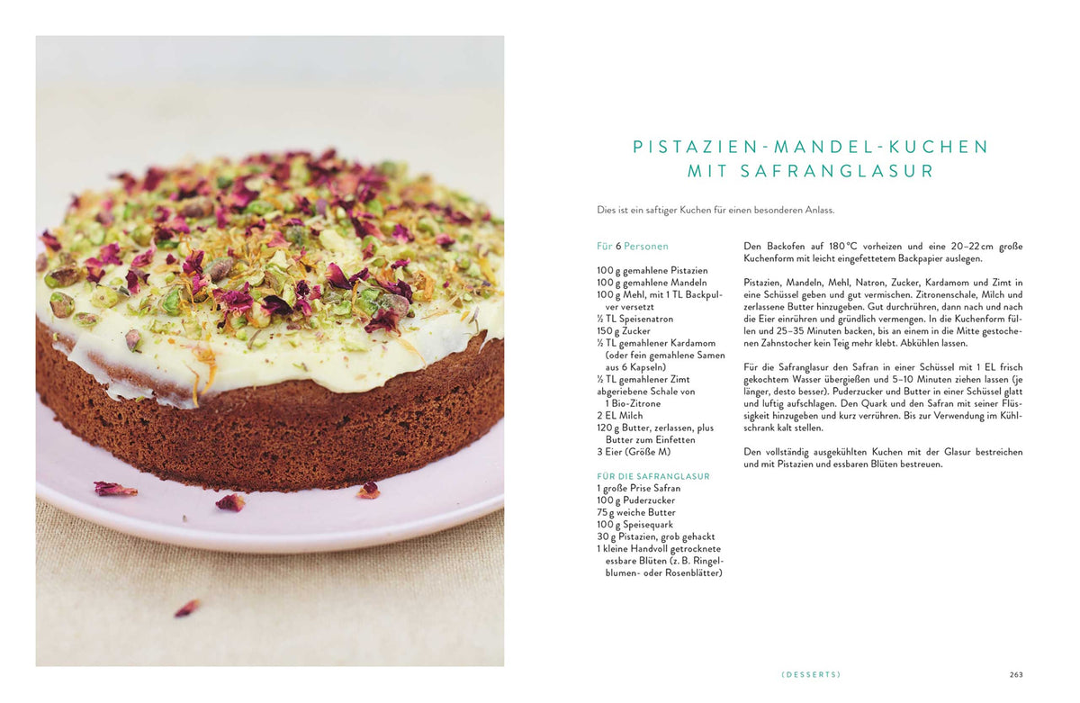 Runder Kuchen mit weißer Glasur, bestreut mit Pistazienstücken und getrockneten Rosenblättern.