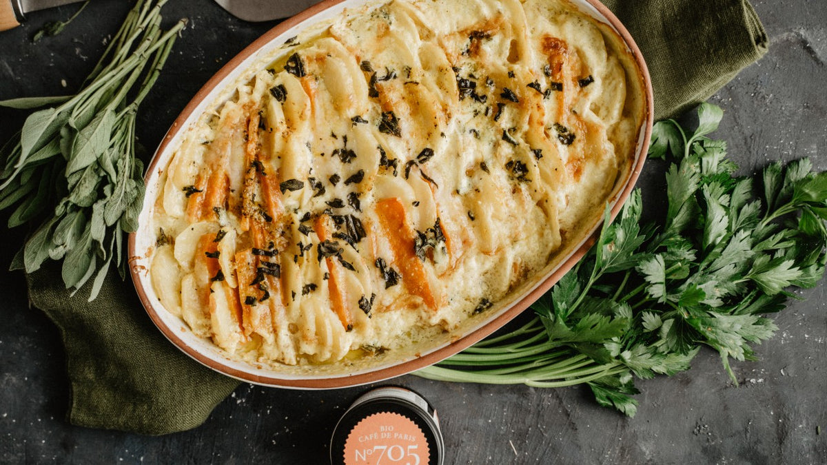 Ovale Auflaufform mit Kartoffelgratin und Kräutern, umgeben von frischen Salbeiblättern.