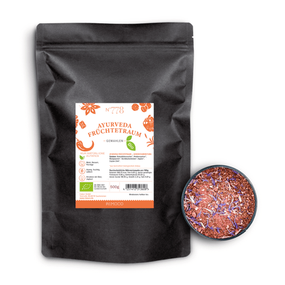 Bio Ayurveda Früchtetraum Kräutertee in schwarzem Beutel neben einer Schale mit losem Teeblatt-Mix.