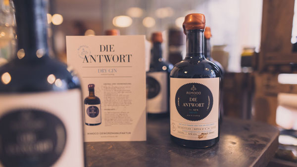 Die Antwort - BIO Gin Flasche mit Informationskarte auf Holzoberfläche.