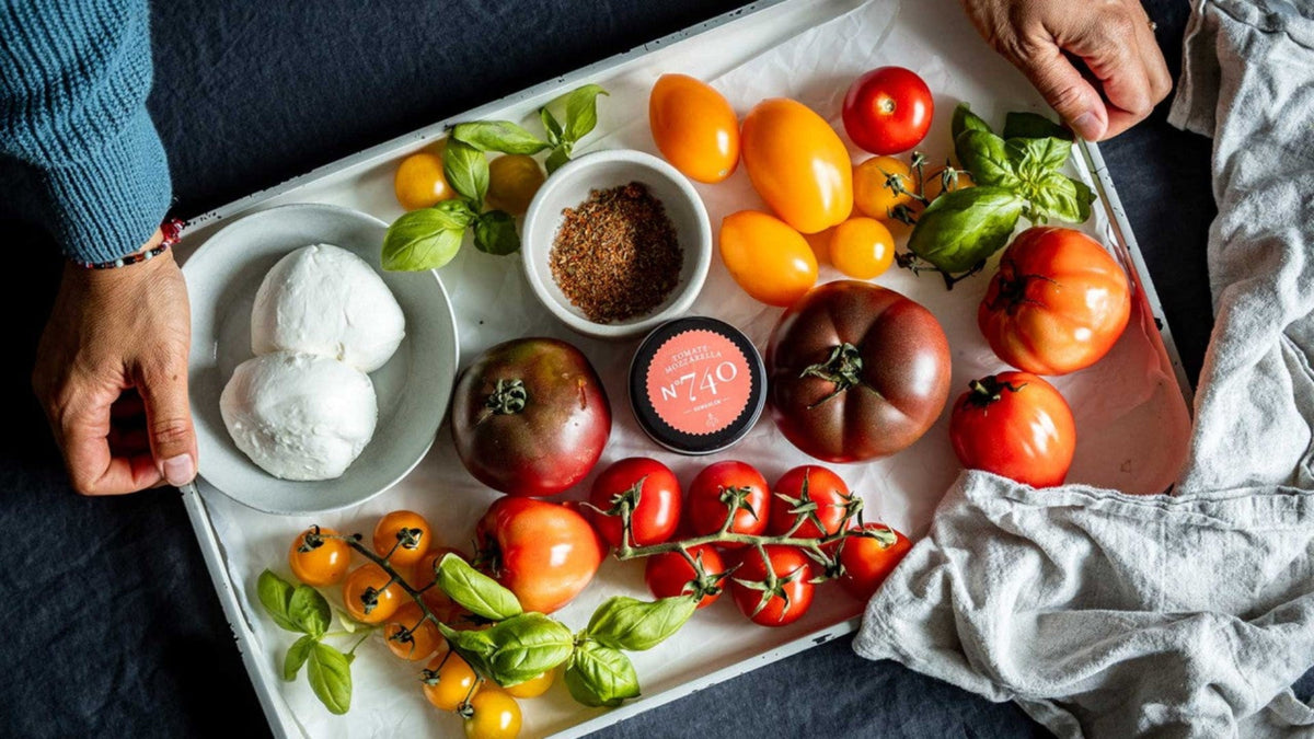 Frische Tomaten, Mozzarella, Basilikum und eine gut sichtbare Gewürzmischung auf einem Serviertablett.