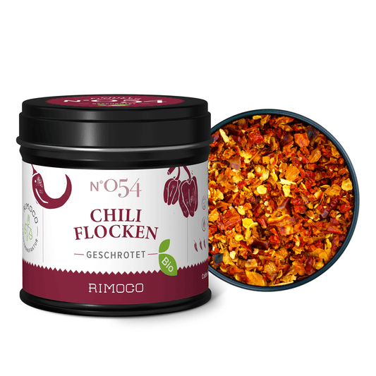 Dose Bio Chiliflocken steht neben einer Schale mit bunten getrockneten Chilischoten.