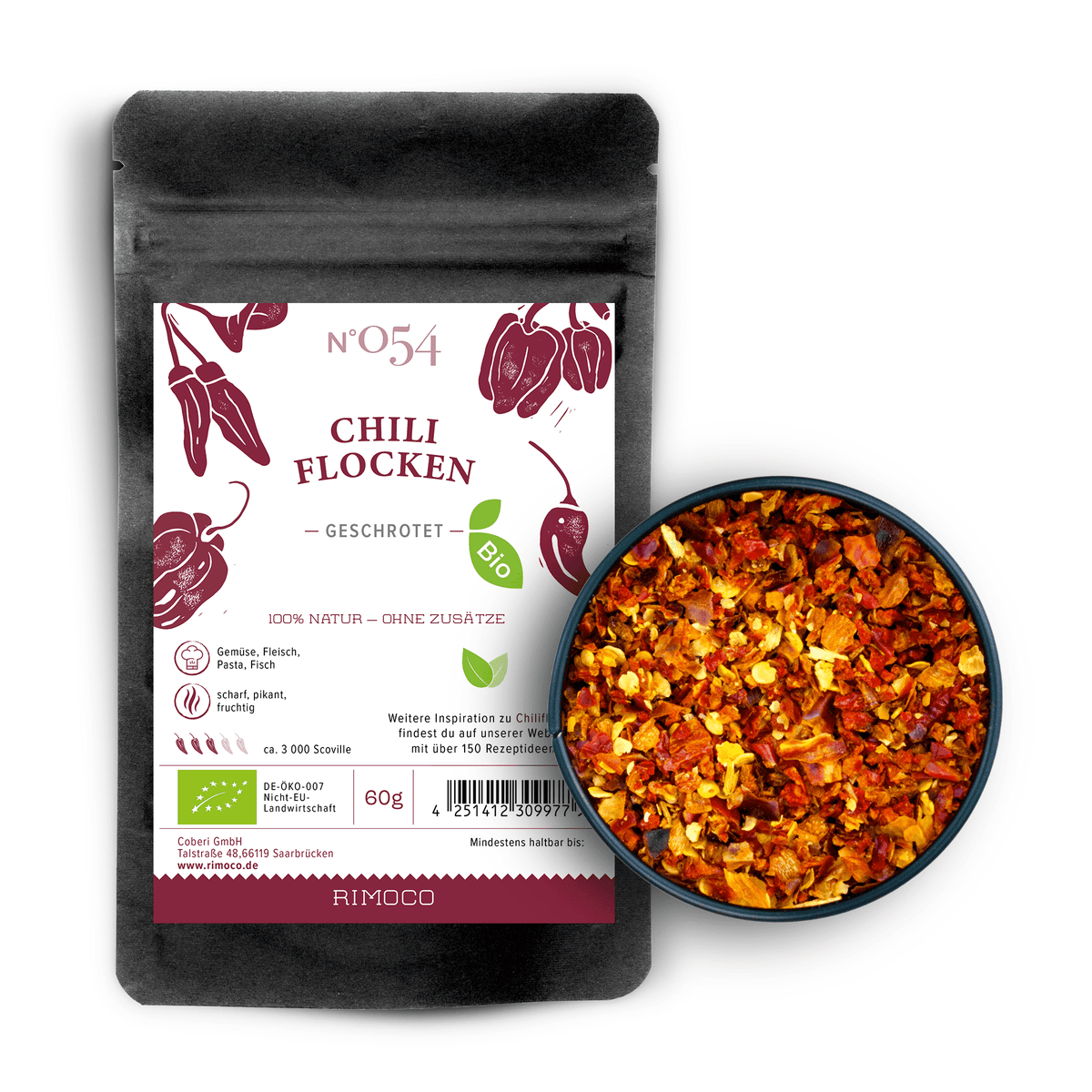 Schwarze Bio Chiliflocken-Packung neben einer Schale mit bunten, getrockneten Chilischoten.