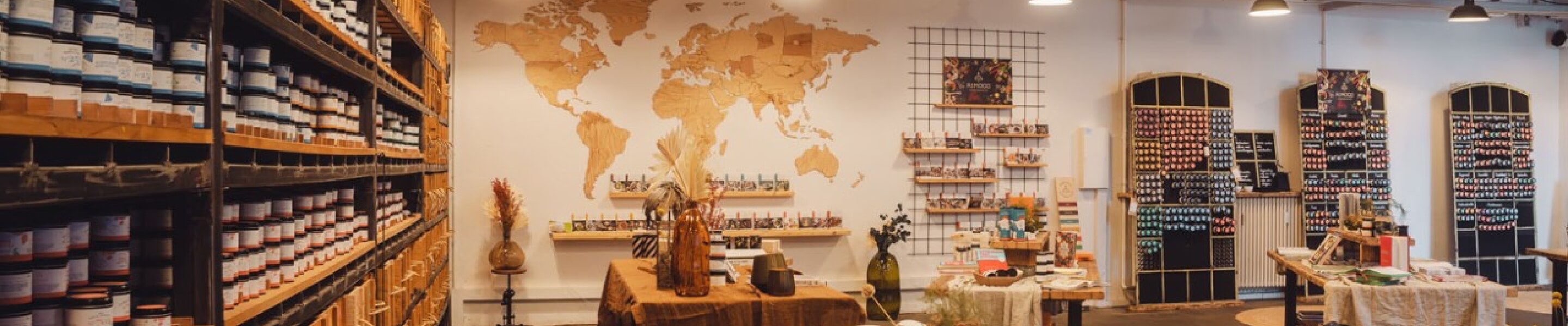 Ein gemütlicher Laden mit Regalen voller Gläser, einer Weltkarte an der Wand und ausgewählten Artikeln auf den Tischen.