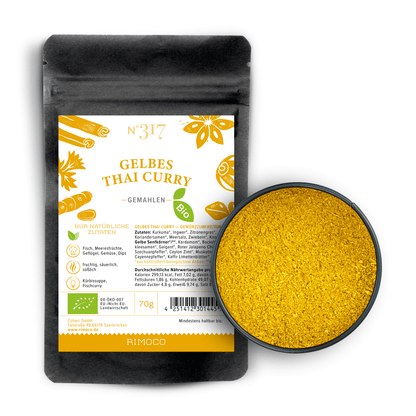 Schale mit leuchtend gelbem Currypulver neben einer Packung Bio Gelbes Thai Curry.