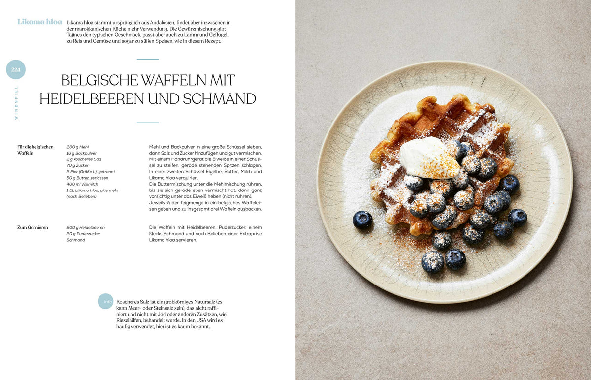 Ein Teller mit belgischer Waffel, Blaubeeren, Sahne und dem Buch Geschenkset Gewürze - Das Kochbuch.