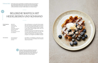 Ein Teller mit belgischer Waffel, Blaubeeren, Sahne und dem Buch Geschenkset Gewürze - Das Kochbuch.
