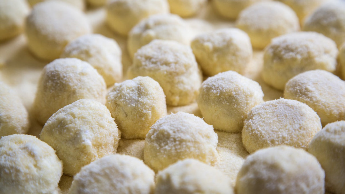 Nahaufnahme von ungekochten Kartoffelgnocchi, die auf einer bemehlten Fläche mit Mehl bestäubt sind.