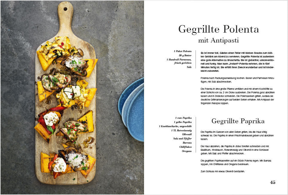 Polentascheiben mit Grillgemüse auf Holzbrett, daneben blaue Teller.