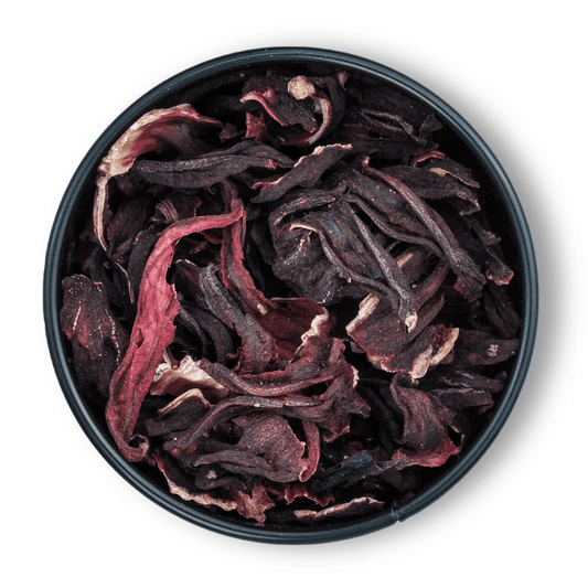 Schale mit ganzen Bio Hibiskusblüten von oben auf weißem Hintergrund.