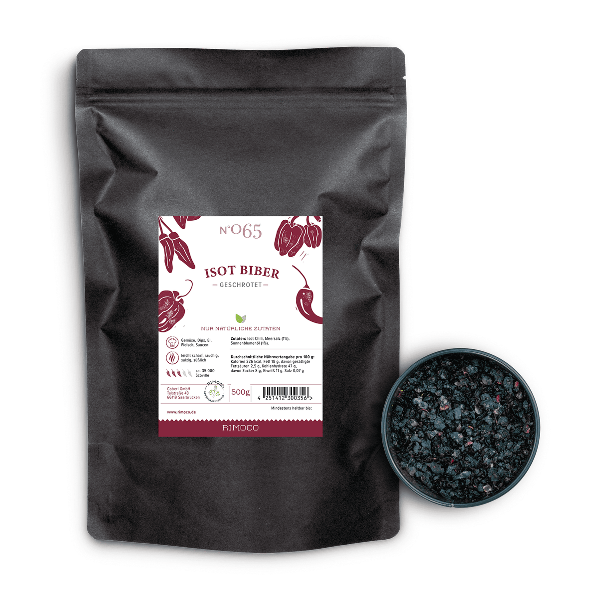 Schwarzer Beutel Isot Biber Chili neben einer Schale mit dunklen, aromatischen Chiliflocken.