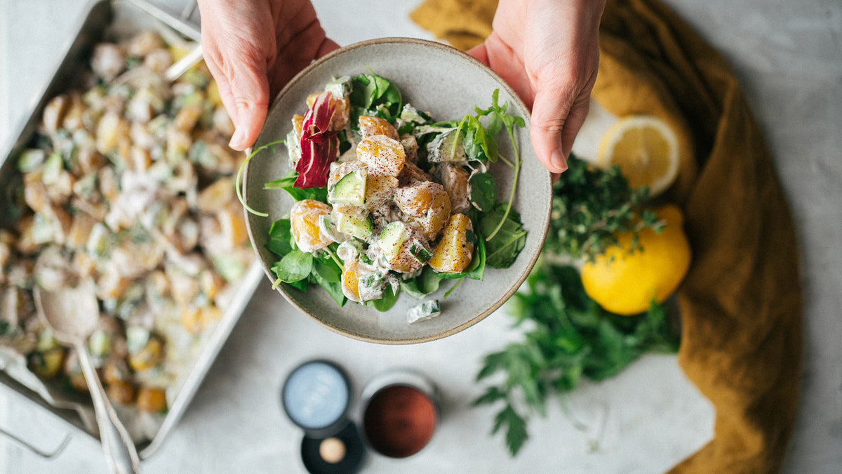 Salat mit Blattsalaten und Avocado, daneben das Gewürzset Ottolenghi Simple auf einem Tisch mit Zutaten.
