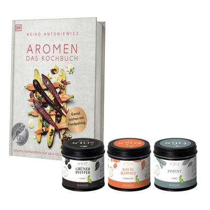 Kochbuch mit drei Gewürzdosen: Grüner Pfeffer, Ras el Hanout und Piment.