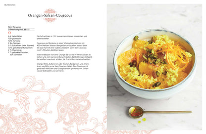 Eine Schale Safran-Couscous mit Orangenscheiben und Pistazien.