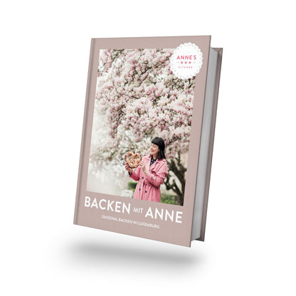 Frau in rosa Kleidung mit Gebäck, Buchtitel: Geschenkset Backen mit Anne.