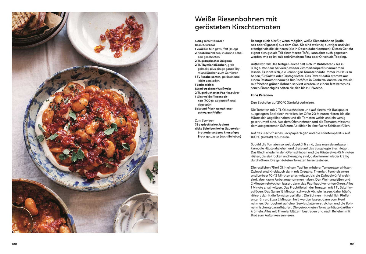 Weiße Bohnen mit gerösteten Kirschtomaten und sichtbaren Kräutern auf einem Teller.