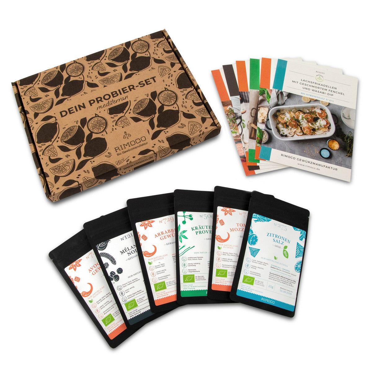 Fünf Gläser mediterrane Bio-Gewürze, Rezeptkarten und braune Boxen nebeneinander angeordnet.