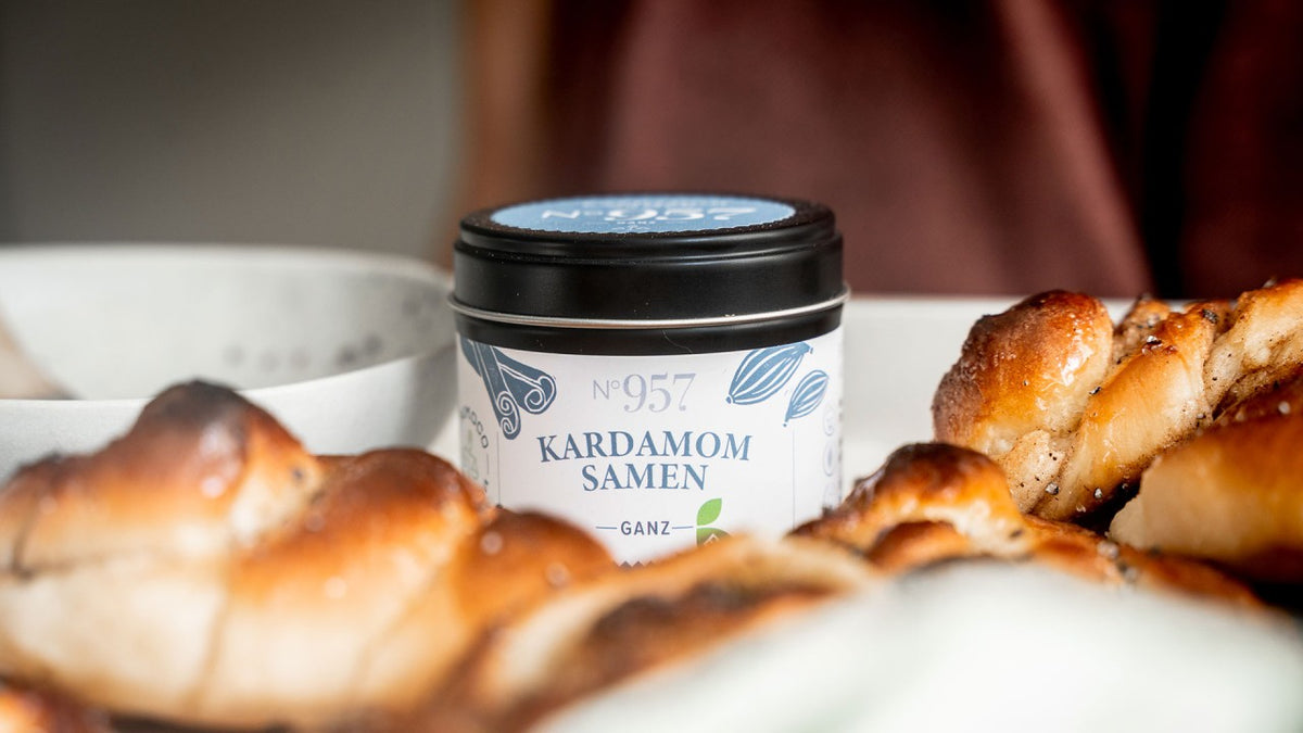 Goldbraune, geflochtene Backwaren, daneben eine Dose „Kardamomsamen“.