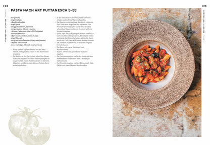 Schüssel Pasta mit Tomatensauce und Kräutern auf rustikalem Untergrund neben einer Rezeptseite.