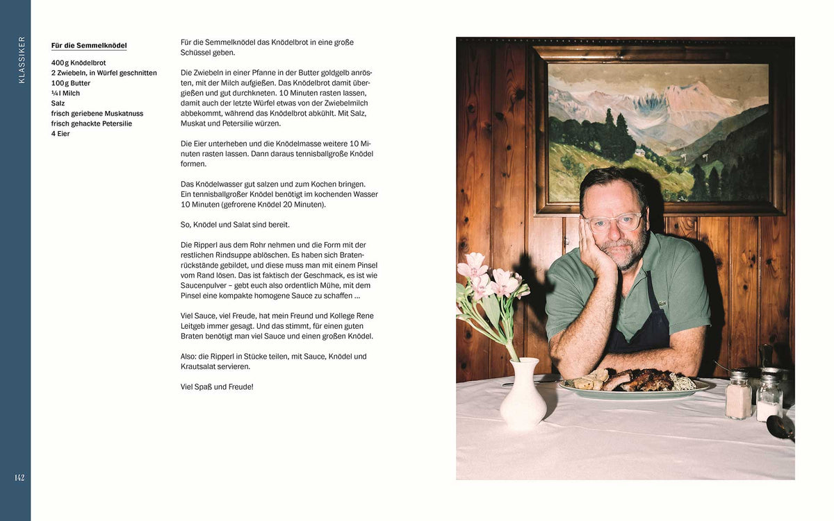 Ein Mann mit Brille isst neben Blumen und Geschenkset Sepp, was machst du? in holzvertäfeltem Raum.