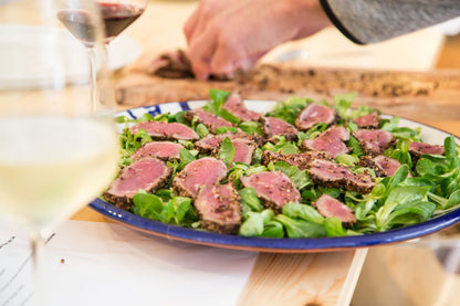 Scheiben Thunfisch auf Salat, dazu ein Glas Wein, im Hintergrund etwas von Gewürzseminar Weihnachten.