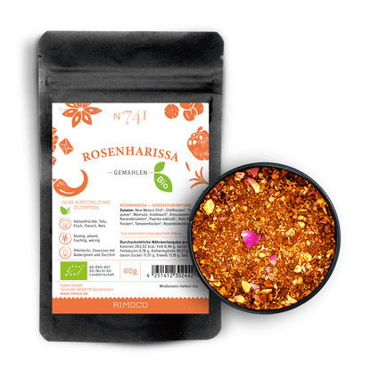 Rosenharissa in einer Schale und im Beutel, mit getrockneten Kräutern und Rosenblättern sichtbar.