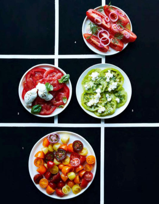 Vier Teller mit Tomaten, Kräutern und Käse.