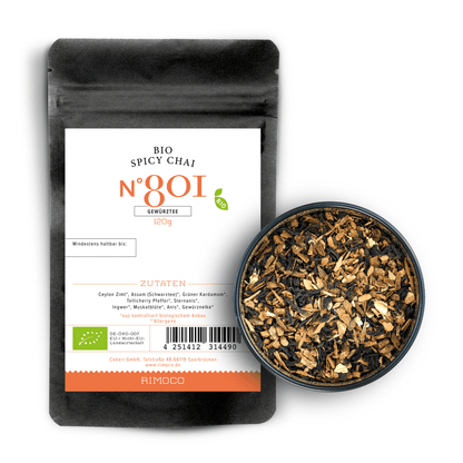 Bio Spicy Chai Tee mit Assam Schwarztee neben einer Schale mit grobem, losem Chai-Gewürz.