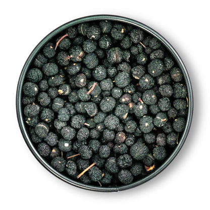 Runde Dose mit getrockneten schwarzen Maulbeeren und tasmanischem Bergpfeffer auf weißem Hintergrund.