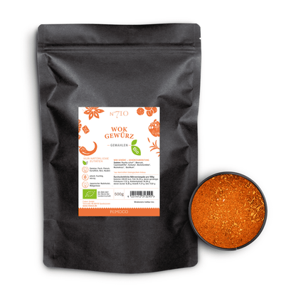 Schwarzer Beutel mit Aufschrift Bio Wok Gewürz neben einer Schale mit orange-rotem Gewürzpulver.